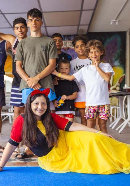 Gruppo di ragazzi sorridenti con Biancaneve, atmosfera gioiosa e colorata.