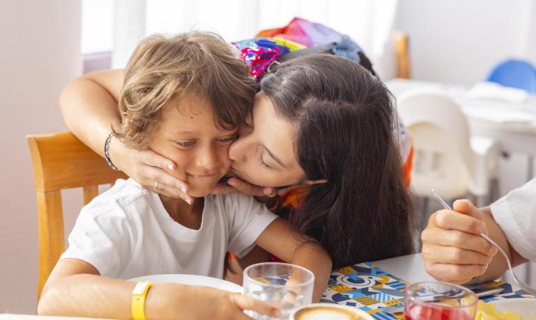 Bacio affettuoso tra madre e figlio, atmosfera di calore familiare.