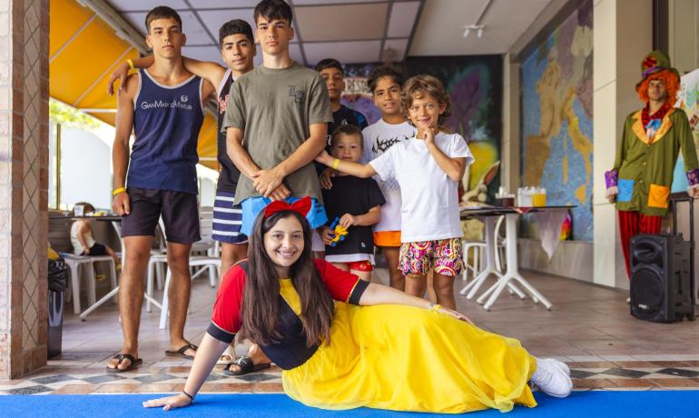Gruppo di ragazzi sorridenti con Biancaneve, atmosfera gioiosa e colorata.