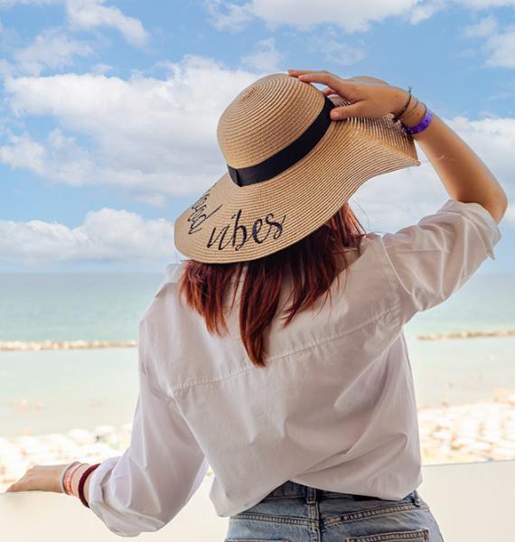Donna con cappello guarda il mare, trasmette libertà e serenità.