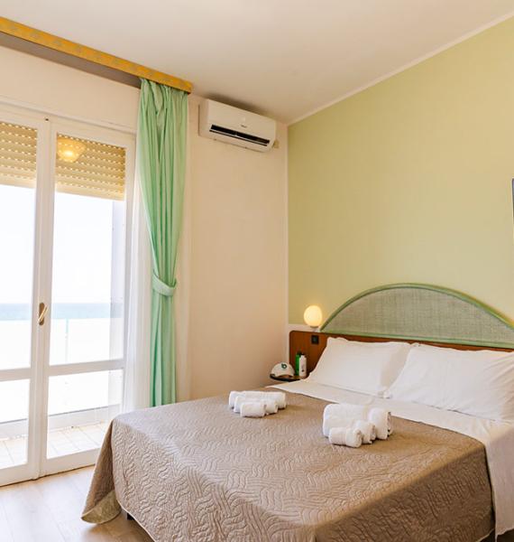 Camera luminosa con vista mare, letto matrimoniale e letti a castello.