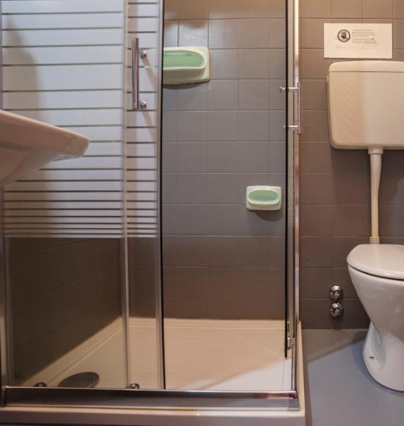 Bagno compatto e funzionale, piastrelle grigie, doccia moderna e servizi igienici essenziali.